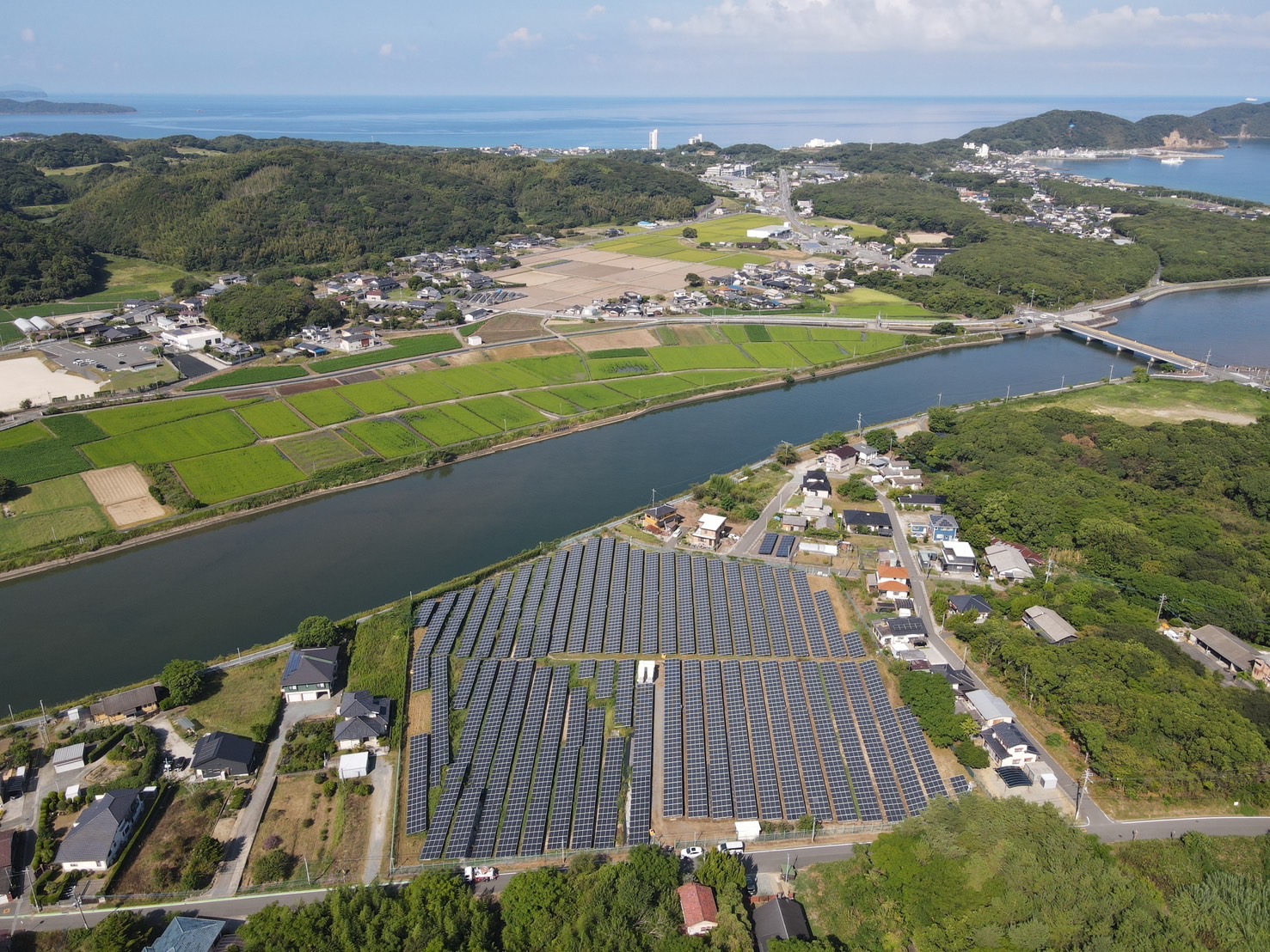 水辺と緑に囲まれた太陽光発電設備の空撮写真